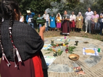 Teilnehmende des Forums in Oaxaca, die im Kreis für ein Ritual um Ernteprodukte und Blumen stehen