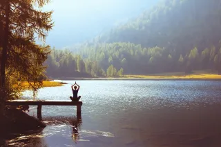 Woman doing yoga on a jetty by a lake