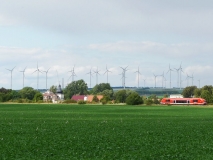 Blick auf die Stadt Guthmannshausen in Thüringen mit Windenergiepark im Hintergrund und Schienenverkehr im Vordergrund