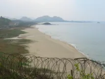 Blick durch Stacheldraht auf Strand