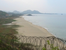 Blick durch Stacheldraht auf Strand