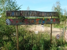 Die Abbildung zeigt ein buntes Schild mit der Aufschrift "Naturerfahrungsraum"
