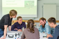 Eine Gruppe von fünf Personen an einem Tisch im angeregten Gespräch