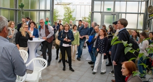 Teilnehmende stehen im Gewächshaus des botanischen Gartens und hören zu.