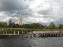 Zu sehen ist das Ufer der Schlei bei Schleswig mit dem landschaftsprägenden St.-Petri-Dom im Hintergrund.