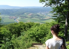 Auf dem Foto ist eine Frau zu sehen. Sie lässt ihren Blick in die weite Landschaft der Hessischen Schweiz schweifen. In der breiten Talaue ist die Werra erkennbar.