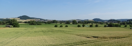 Das Bild zeigt eine landwirtschaftlich genutzte Landschaft. Im Hintergrund sind Basaltkuppen gut erkennbar.