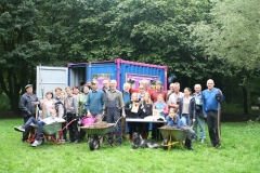 Menschengruppe mit Schubkarren vor einem Container