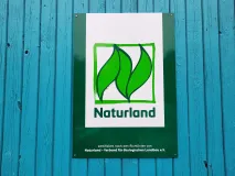 Naturlandlogo an einem hellblauen Scheunentor
