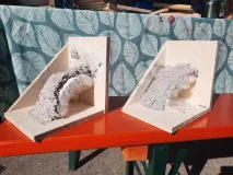 Selbstgebaute Schwalbenwinkel auf einer Bank zum Trocknen ausgelegt. In dem Winkel wurde mit Gips auf einer Styroporkugel ein Nest geformt