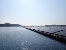 Das Foto zeigt eine schwimmende PV-Anlage, aufgenommen aus einem Boot. Auf der linken Seite ist das freie Gewässer zu sehen, auf der rechten Seite erstreckt sich die PV-Anlage mehrere hundert Meter auf dem Gewässer.