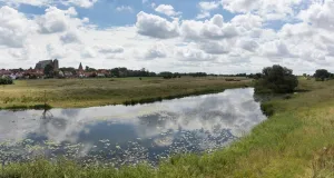 Zu sehen ist die Aller mit ihrer naturnahen Aue, im Hintergrund thront der markante Dom von Verden.