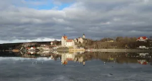 Das Foto zeigt den Ort und das Schloss Seeburg am Süßen See. Ort und Schloss spiegeln sich im zugefrorenen See.