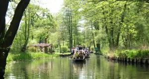 Das Foto zeigt die Hauptspree bei dem Spreewaldort Lehde. Der lichte Erlenbruchwald reicht bis an die Ufer der Spree. Die Spree wird von zwei typischen Spreewaldkähnen mit Touristenbefahren.