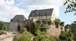 Auf einem Bergvorsprung ist eine Burg zu sehen. Es ist ein leicht bewölkter Frühlingstag.
