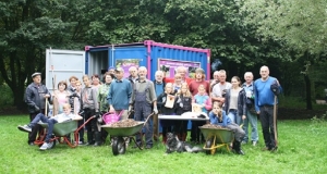 Menschengruppe mit Schubkarren vor einem Container