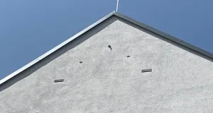 Graue Hausfassade vor blauem Himmel