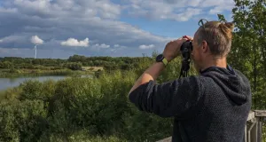 Das Foto zeigt einen Beobachter mit Fernglas auf dem Aussichtsturm in den Rieselfeldern in Münster