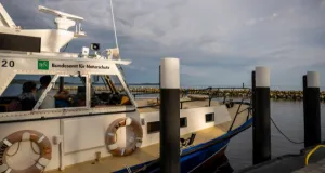 Fahrgastschiff mit der Aufschrift 'Bundesamt für Naturschutz' am Kai bei bewölktem Himmel