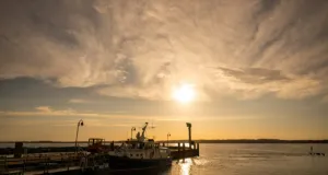 Hafen mit Booten bei Sonnenuntergang und bewölktem Himmel