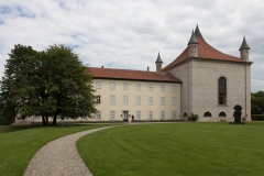 Schloss Derneberg mit einer kurz gemähten Rasenfläche und einem geschwungenen Weg im Vordergrund.