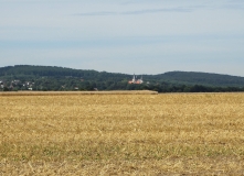 Abgeerntetes Feld. In der Ferne sind der bewaldete Elm und Königslutter mit dem Kaiserdom zu sehen.