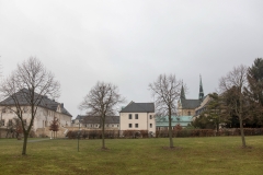 Im Vordergrund ist eine junge Baumgruppe zu sehen. Der Blick führt zur Klosteranlage Huysburg. Es herrscht eine winterliche Stimmung.