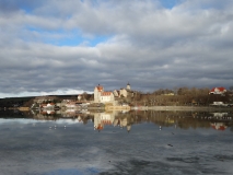 Das Foto zeigt den Ort und das Schloss Seeburg am Süßen See. Ort und Schloss spiegeln sich im zugefrorenen See.