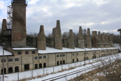 Ein ungenutztes Industriegebäude mit zahlreichen, kegelförmigen Schornsteinen an einem verschneiten Wintertag.