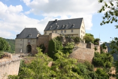 Auf einem Bergvorsprung ist eine Burg zu sehen. Es ist ein leicht bewölkter Frühlingstag.