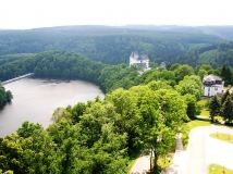 Das Foto zeigt  einen Landschaftsausschnitt des oberen Saaletals mit der Reußischen Residenz Schloss Burgk, einem Teil des Stausees und der Staumauer Burgkhammer. Die umgebende Landschaft ist von geschlossenen Laub- und Nadelwäldern umgeben.