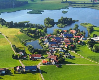 Luftaufnahme von einem Ort, im Hintergrund ein See