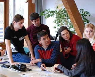 People sit and stand at a table and talk to each other