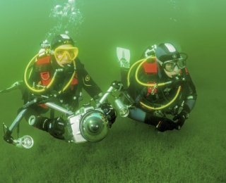 zwei Taucher mit Unterwasserkamera in einem See