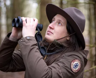Rangerin mit Fernglas beobachtet die Natur