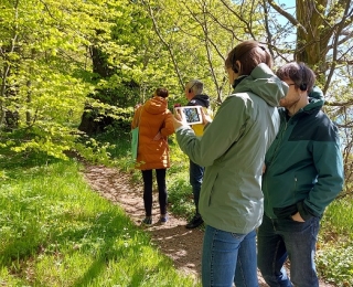 Tagungsteilnehmende testen eine Demoversion der AR-Anwendung, die auf einem Waldlehrpfad im Bürgerwald Eggenfelden zum Einsatz kommt 