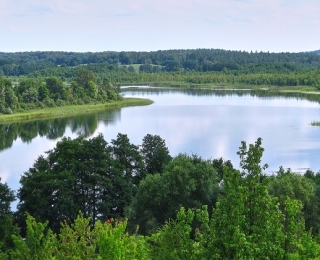 See in einer Hügellandschaft mit Wäldern und landwirtschaftlichen Flächen