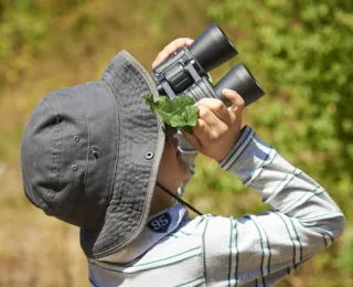 Kind betrachtet mit Fernglas die Natur