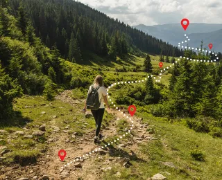 Eine Frau wandert auf einem Pfad. Eine gestrichelte Linie gibt ihre Route vor.