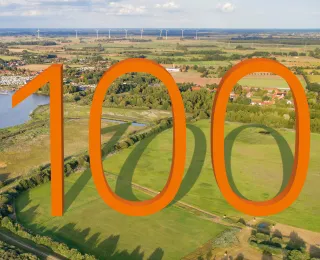 Eine große orangene 100 mit dem Dümmer See im Hintergrund