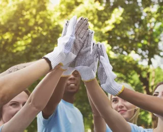 Mehrere Personen tragen Gartenhandschuhe und klatschen sich in der Luft mit den Händen ab