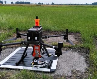 Eine unbemannte Multikopter-Drohne mit montiertem hyperspektralem Sensor steht auf einer Start- und Landeplattform in einem Moorgebiet.