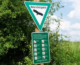 zwei grüne Schilder eines Naturschutzgebietes 