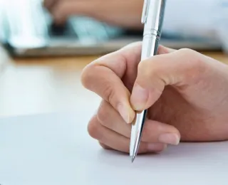 Hand schreibt mit einem Stift auf einen Zettel