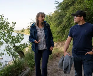 Bundesumweltminister Schneider im Gespräch beim Spaziergang auf einem Waldweg am Wasser entlang