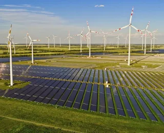 Solarpark und mehrere Windenergieanlagen auf Grünland unter blauem Himme