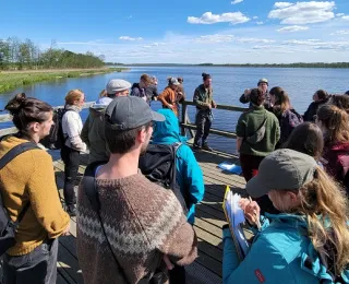 Mehrere Personen stehen auf einem Steg am See 