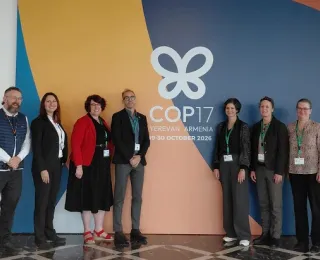Die Delegation des BfN bei der COP in Yerevan steht vor einem Plakat der COP
