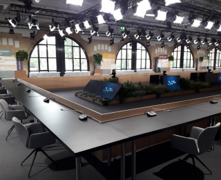 Auf der Abbildung sieht man einen Sitzungsaal mit Logo der deutschen Ratspräsidentschaft.