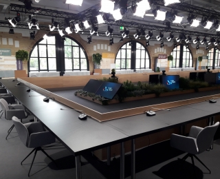 A conference room with screens showing the German EU Council Presidency logo